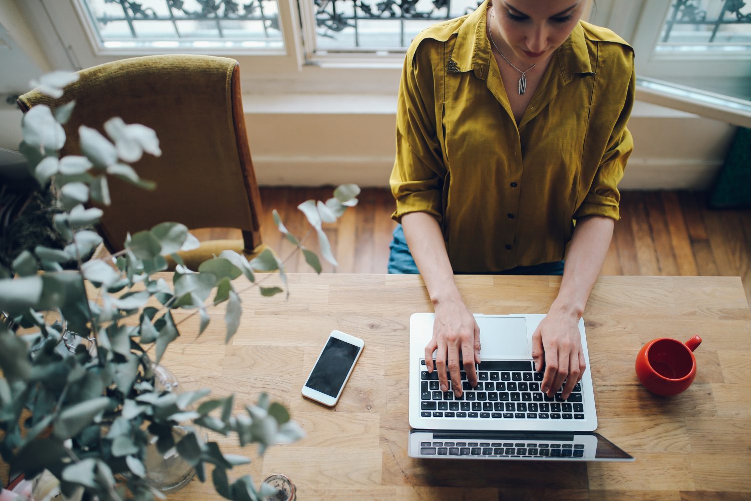Stock photo of a freelance writer typing on her computer, taken from an overhead angle. It's to demonstrate the title 4 Common Mistakes That Could Destroy Your Freelance Writing Career